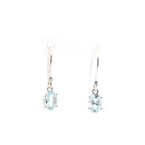 Faceted aquamarine dangle earrings with oval gemstones set in silver, showcasing a light blue color.