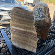 Serpentine onyx layered boulder fountain with one flat cut side, water bubbling over honey-banded rock