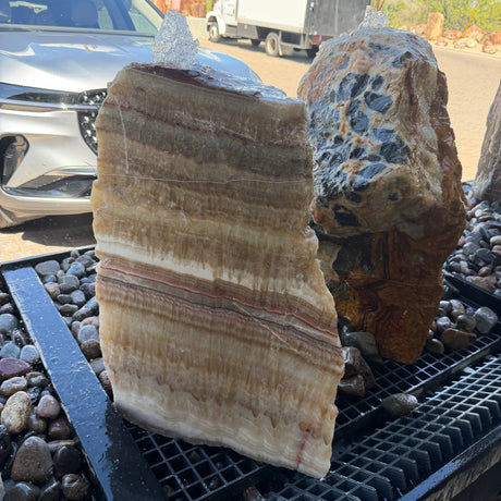 Serpentine onyx layered boulder fountain with one flat cut side, water bubbling over honey-banded rock