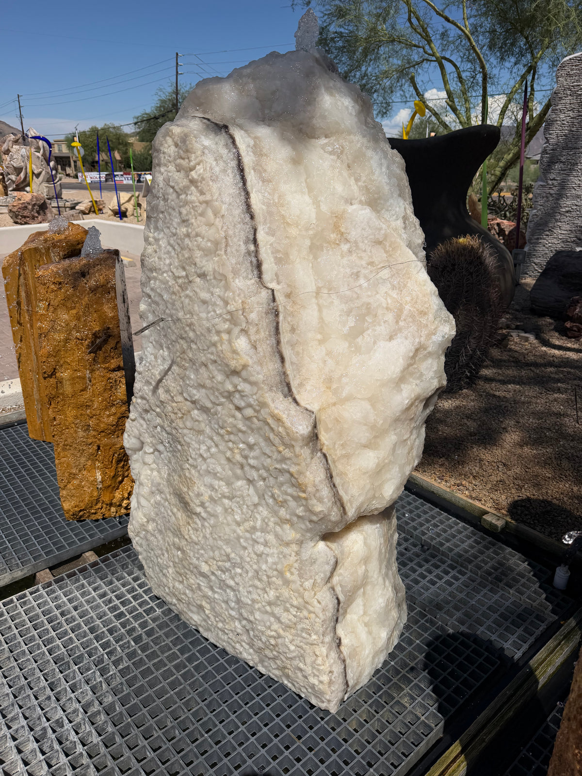 White crystal and gray onyx band fountain running outdoors, sparkling textured crystal face on a drain grate