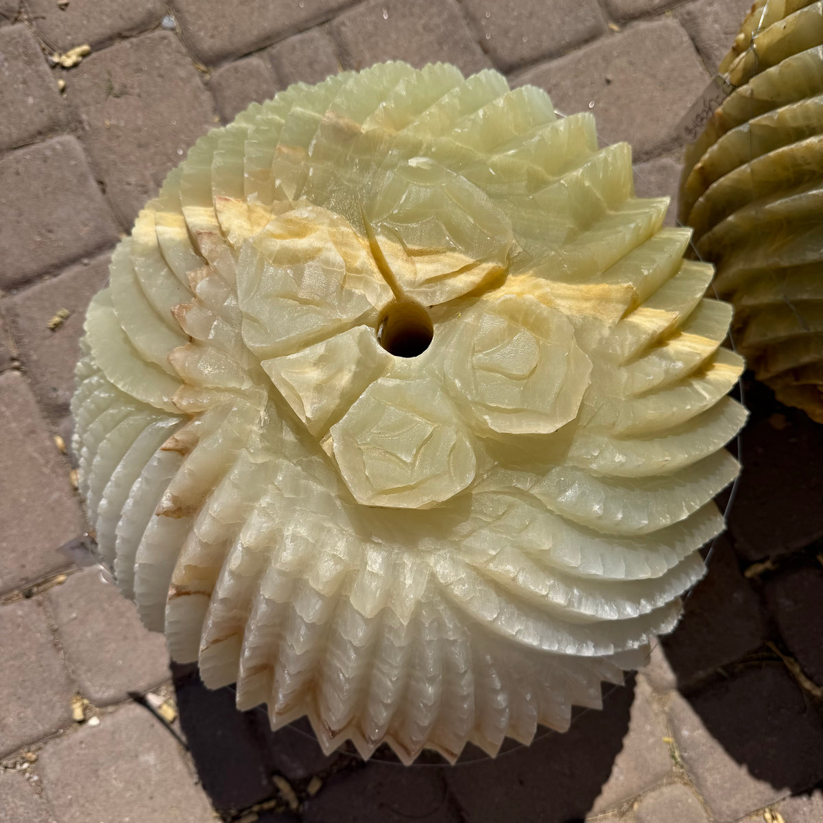 Top-down view of carved rosettes ringing the cactus fountain's drilled center opening