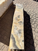 Cosmic onyx fountain pillar on a pallet, wavy cut side with honey and gray banding, viewed from above