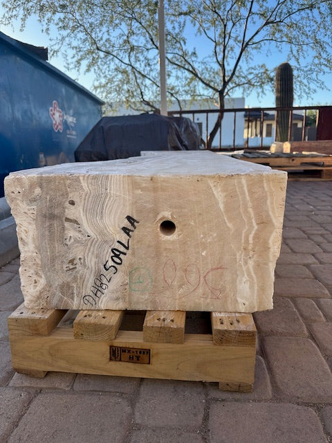 End view of the amber onyx fountain block on a pallet, drilled center hole and inventory markings visible
