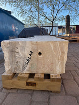 End view of the amber onyx fountain block on a pallet, drilled center hole and inventory markings visible