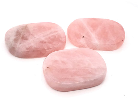 Three polished rose quartz flat stones in pale blush pink with soft white swirls on a white background