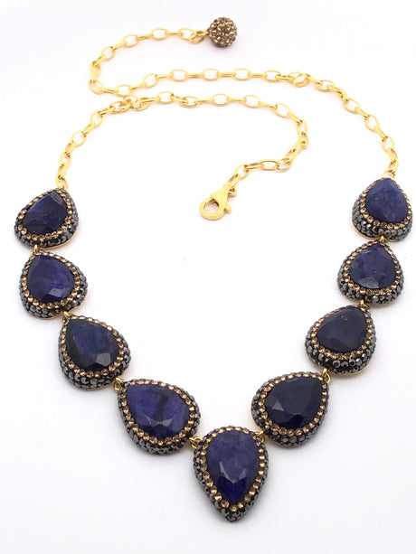 Necklace with blue teardrop-shaped pendants and gold chain on a white background