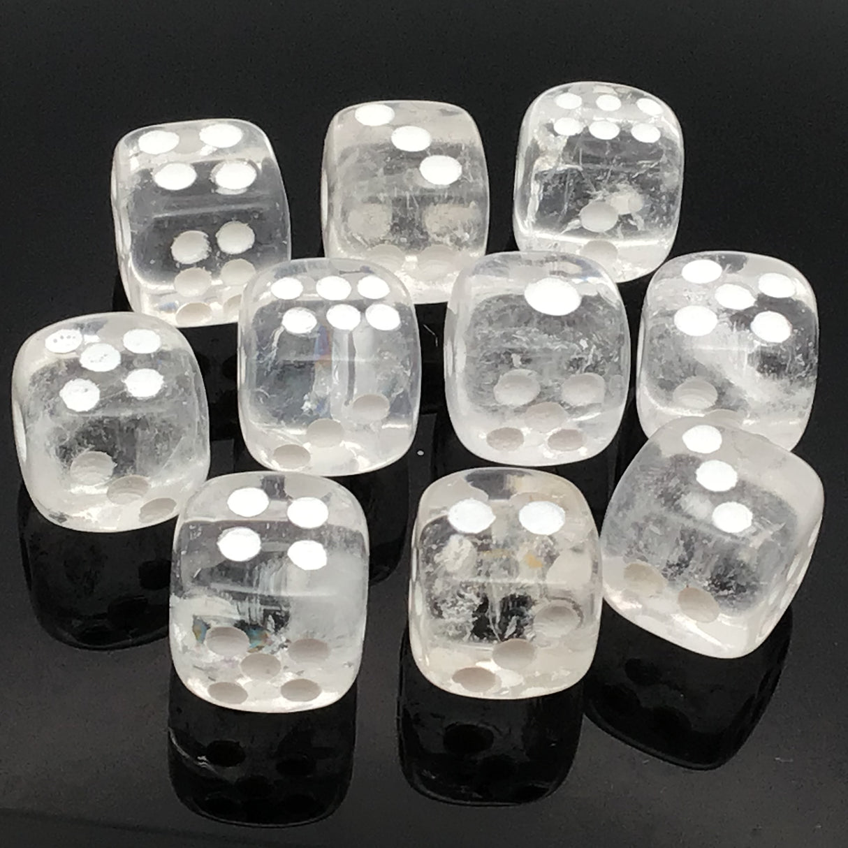 Clear quartz dice carvings set of 10, featuring translucent white dice with silver dots on a black reflective surface.