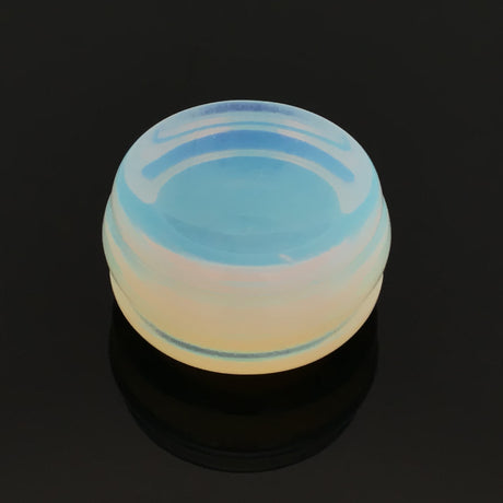 Opalite gemstone sphere stand disc with carved cradle glowing blue and peach on a black reflective surface