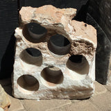 Six-hole rustic onyx wine rack in pale white and blush stone with a rugged unpolished top edge