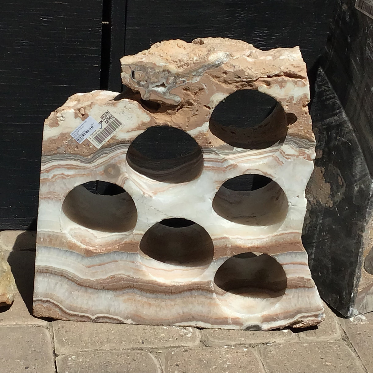 Rustic onyx wine rack with 6 holes and horizontal brown and cream banding across a rough-edged stone slab