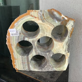 Green banded rustic onyx wine rack with 6 holes and an amber rind, displayed on a black pedestal