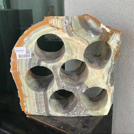 Green banded rustic onyx wine rack with 6 holes and an amber rind, displayed on a black pedestal