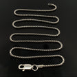 18-inch round box chain 028 coiled in an S curve on glossy black with the lobster clasp at front