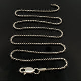 18-inch round box chain 028 coiled in an S curve on glossy black with the lobster clasp at front