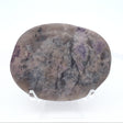 Oval palm stone, pale mauve and gray with scattered purple flecks, upright on a clear stand