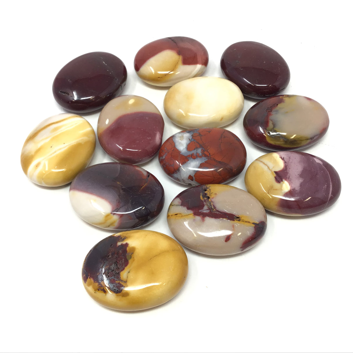 Twelve polished Mookaite Jasper palm stones in burgundy, mustard and cream tones arranged on white