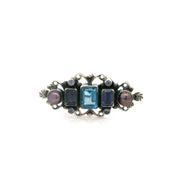 Tanzanite brooch front with emerald-cut violet stones, blue topaz center, pearls and silver beading