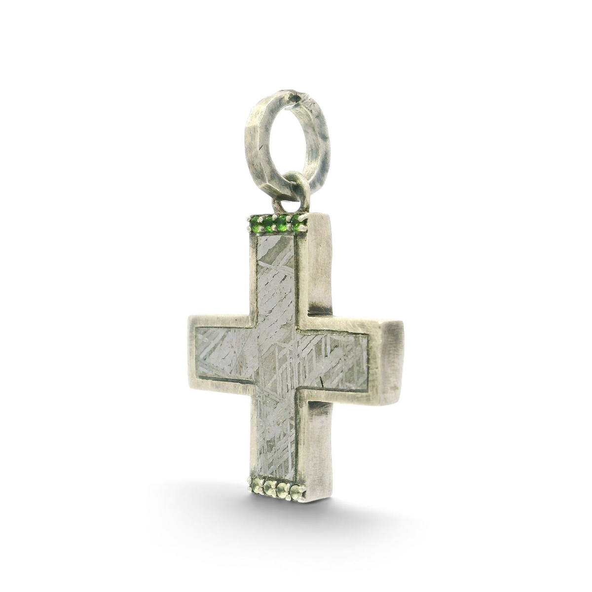 Angled view of Muonionalusta meteorite cross pendant showing silver bezel edge and hammered bail
