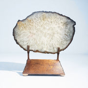 Agate slice with dark brown trim and white crystalline center on a rustic copper-toned metal stand
