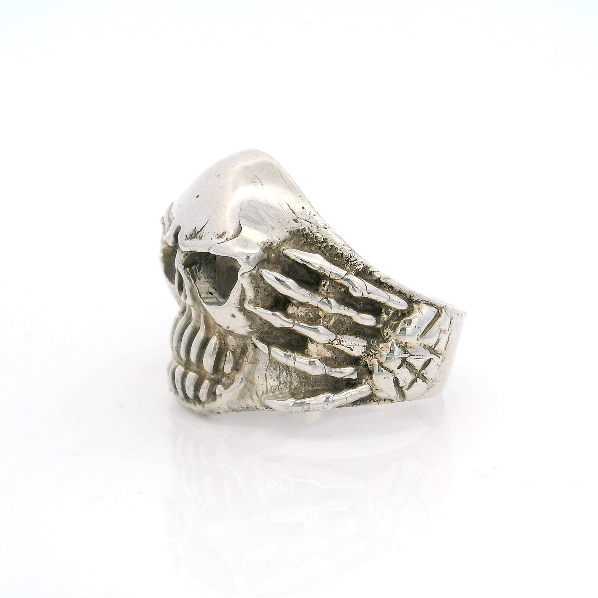 Sterling silver cracked skull ring, side view showing skeletal hand gripping the band