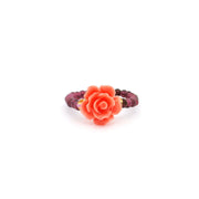 Carved pink opal rose flanked by gold beads on a red garnet bead stretch band, front view
