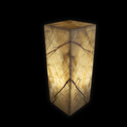 Cherry Blossom caramel onyx luminary pedestal illuminated, glowing amber column with book-matched veining on black