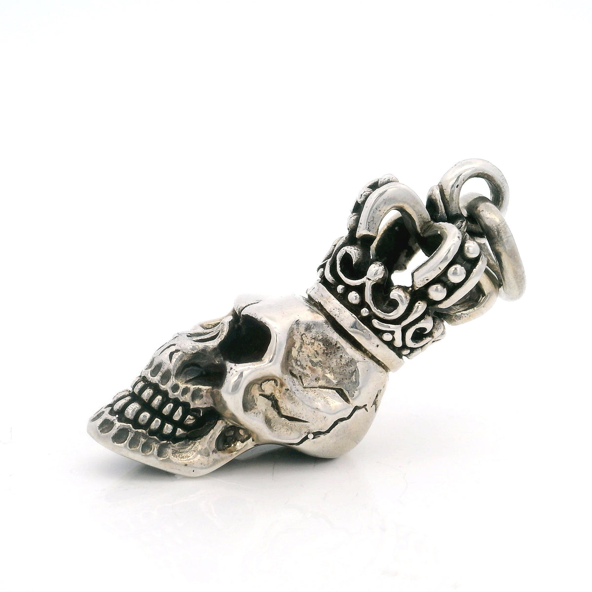 Angled view of the sterling silver skull pendant topped with an ornate scrollwork crown