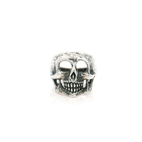 Sterling silver skull ring with hollow eye sockets and grinning teeth in an oxidized finish