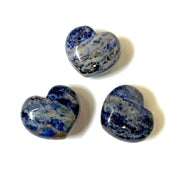 Three polished sodalite puffy hearts with royal blue and white marbling on a white background