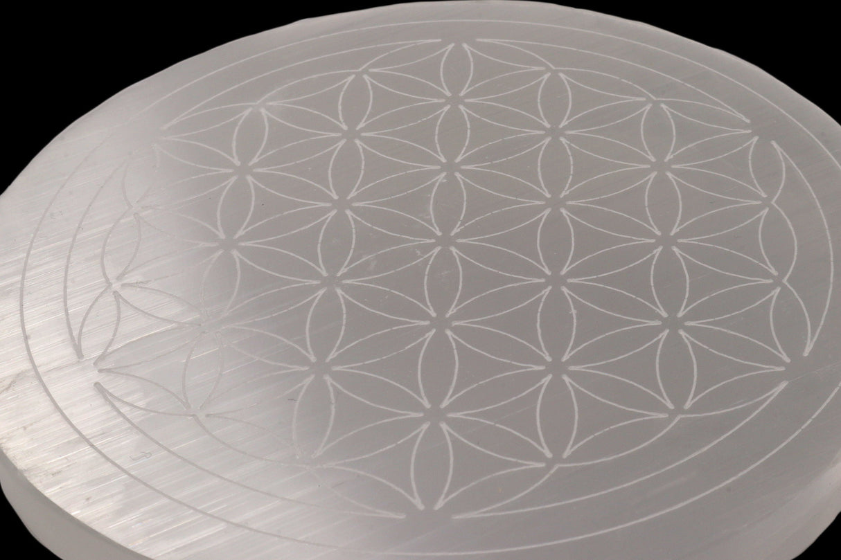 Close-up of the engraved Flower of Life pattern on a translucent selenite disc
