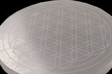 Close-up of the engraved Flower of Life pattern on a translucent selenite disc