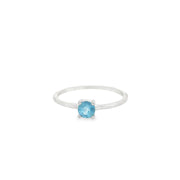 Dainty aquamarine solitaire ring with a prong-set round blue stone on a thin rhodium vermeil band