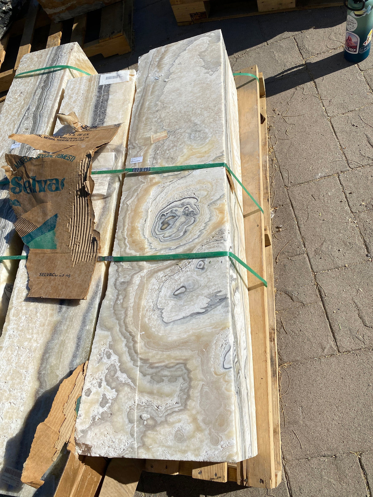 Zebra fossil onyx pillar fountain strapped to a wooden pallet, orbital eye patterns in cream and gold banding