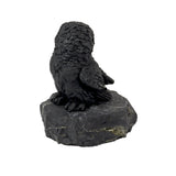 Shungite owl figurine seen from the side, showing detailed carved back and wing feathers on stone base
