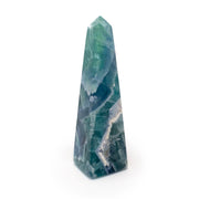 Tall rainbow fluorite obelisk in teal and green with a sparkling druzy seam near the base