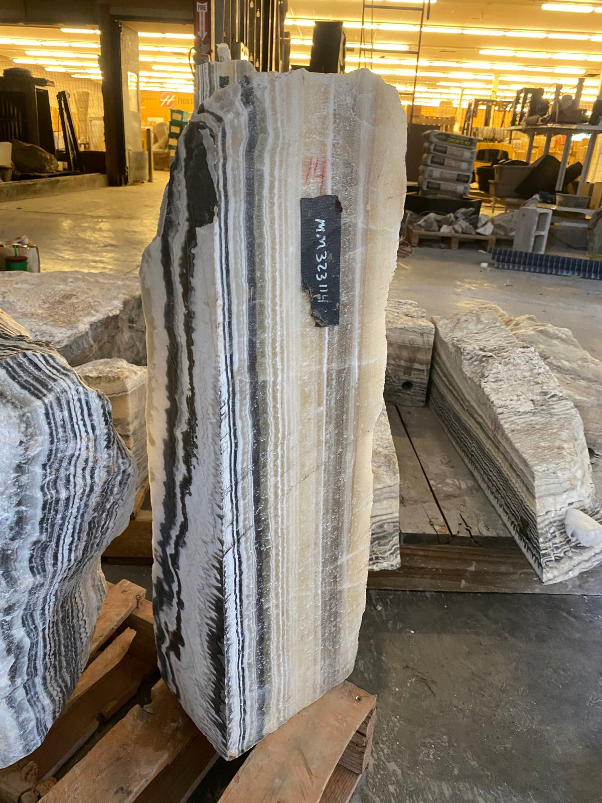 Tapered Yellow Zebra Onyx pillar fountain with bold black and cream striping in a stone warehouse