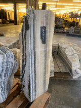 Tapered Yellow Zebra Onyx pillar fountain with bold black and cream striping in a stone warehouse