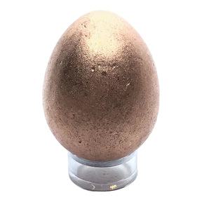 copper egg on a clear stand against a white background