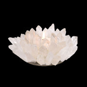 Quartz crystal point tea light candle holder lit with a glowing flame on black