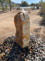Tekkis Onyx boulder fountain running on a river rock bed, white and rust banded monolith in a desert yard