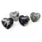 Four polished zebra jasper hearts showing black, white and gray striping on a white backdrop