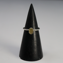 Rough freeform Egyptian tektite in a silver bezel on a thin band, shown on a black cone stand