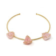Gold wire-wrap collar necklace with three raw rose quartz gems, angled flat-lay on white