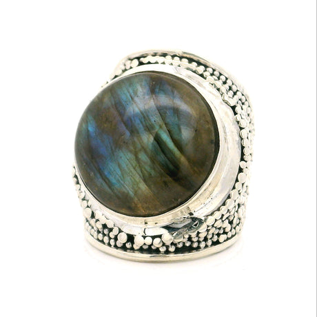 A sterling silver ring featuring a large oval cabochon labradorite gemstone with iridescent blue, green, and brown flashes, set against a plain white background.