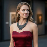 Rare Earth Gallery ammonite fossil necklace set with black spinel and black star garnet, on a model wearing a red dress.
