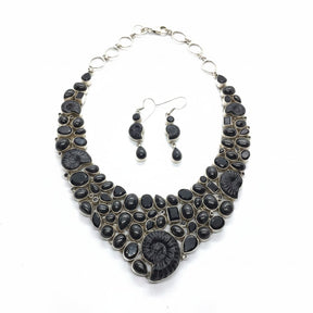 Rare Earth Gallery ammonite fossil necklace set with black spinel and black star garnet. Features spiral ammonites and mixed-cut black gemstones.