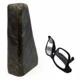 Rare Earth Gallery polished labradorite freeform stone with iridescent blue and gold flashes next to black glasses