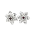 A pair of silver flower-shaped stud earrings with a small round dark red gemstone in the center of each flower, set against a plain white background.