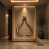 Two curved mammoth tusks displayed upright on a beige wall in a warmly lit interior setting.